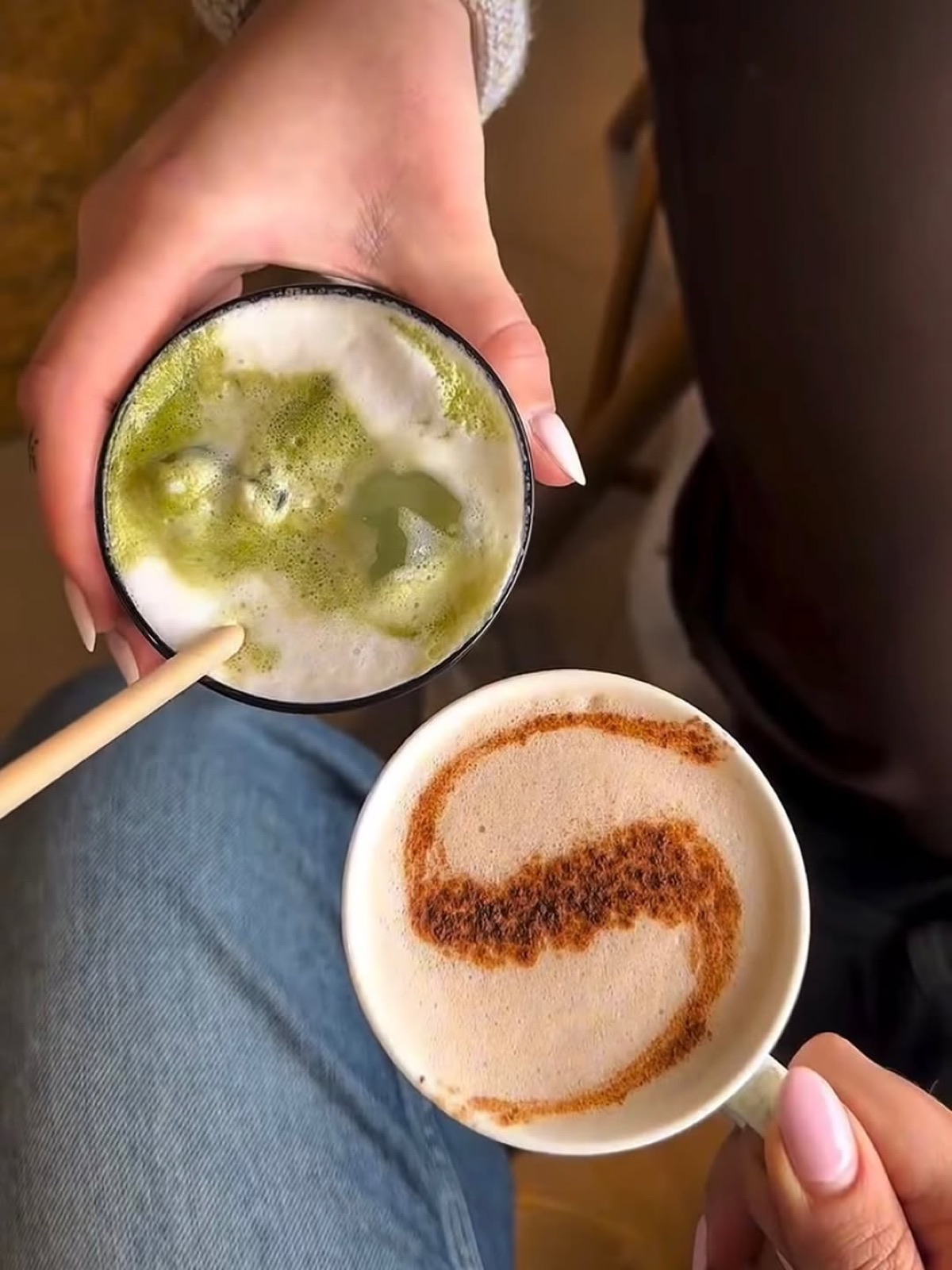 A matcha latte and a flat white held side by side