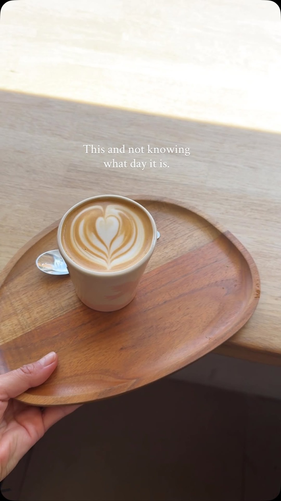 A latte on a wooden tray, "this and not knowing what day it is"