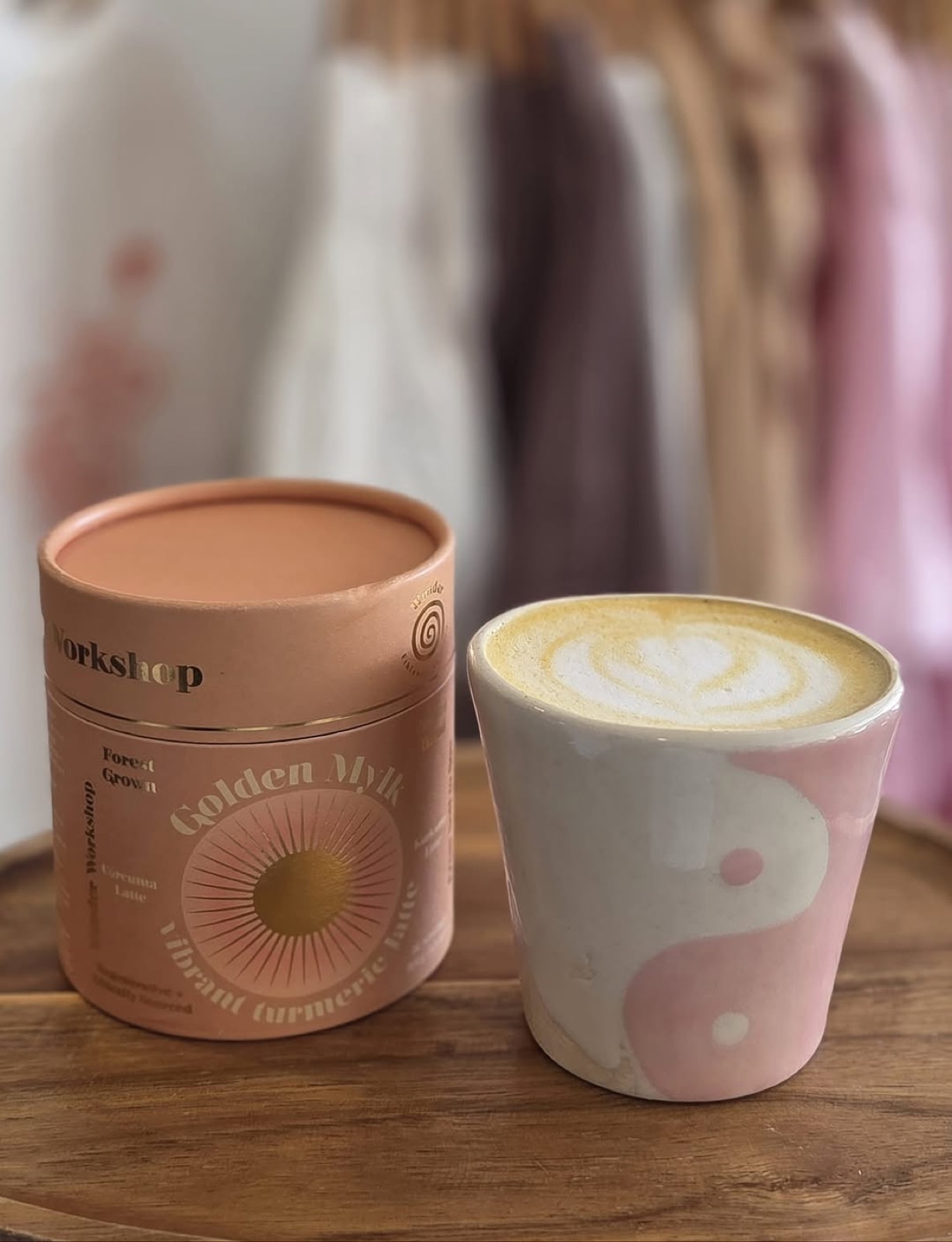 A latte on the table with the clothing rail blurred behind it